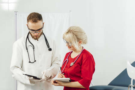 Close up portrait of two medical doctors standing in a hospital office and looking at camera. Doctors in uniform, man and woman in a gynecological officeの写真素材