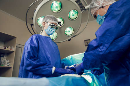 Bottom view, two surgeons perform the operation in a hospital. Side view of young doctors at work. Surgery conceptの写真素材
