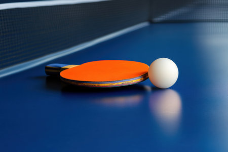 A table tennis paddle and ball on a tournament table.の写真素材