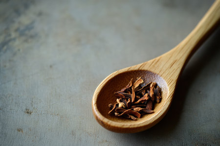 A wooden spoon holds rich clove oil, a natural remedy known for soothing toothaches. The high definition capture highlights the oil's essence and the spoon's texture.の写真素材