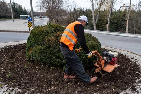Gardener is working on soil with a machine