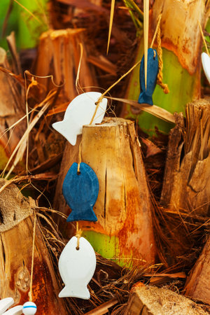 wooden garden decor in the shape of fish on a palm tree in a charming gardenの写真素材