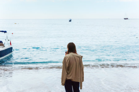 girl in clothes walking along the beach shoreの写真素材