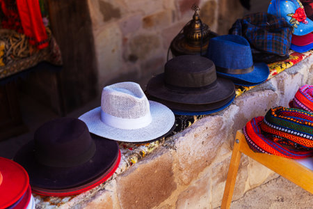 A collection of various hats is currently resting on a stone wall