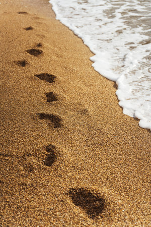 Beautiful wave on sandy beach with footprintsの写真素材