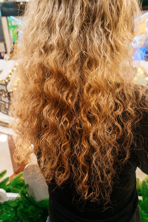 the girl has long dyed hair. blonde curly hair of a womanの写真素材