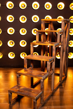 wooden staircase against wall of incandescent light bulbs. wall of spotlights with large staircaseの写真素材