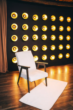armchair with light fabric against of incandescent lamps. area with armchair and bright floor lamps