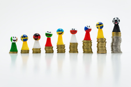 Pawns with smiling faces in flag colors, standing on growing coins. The concept of competition and victory.の写真素材