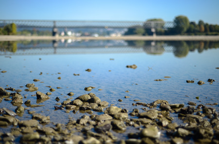 Landscape with a river, stones and a railway bridge. River Rhine in Germany.