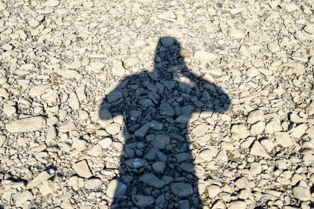 A shadow of a man on stones making a photo. River Rhine in Germany.の写真素材