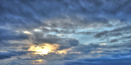 Cloudy, blue, rainy sky with clouds and sun. Colorful evening nature.の写真素材