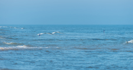 Rough waves on a beautiful blue sea on a sunny, sunny and windy day. Protruding warning flags from the sea.の写真素材