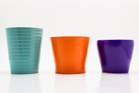 Three flower pots in turquoise, orange and purple colors isolated on a white background.の写真素材