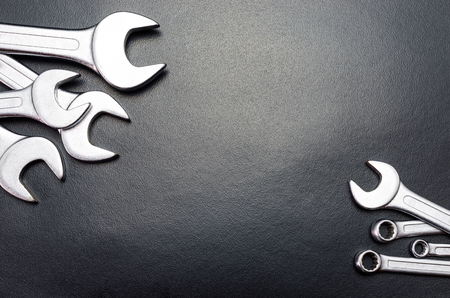 Metal flat wrenches lying on a black table, top view, flat lay.