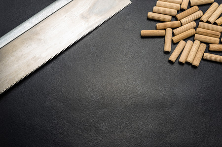 A lot of wooden pegs and hand saws on a black background.の写真素材
