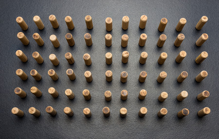 A lot of wooden pegs standing vertically on a black background.の写真素材
