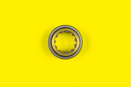 Single ball bearing close up, isolated on yellow background with copy space on the sides.の写真素材