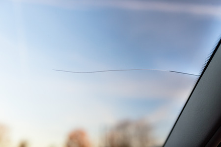 A long rupture of the windshield in the car, from the cars pillar to the center. Blue sky in the...