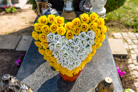 Artificial flowers in the shape of a heart and candlesticks lie on the tombstone in the cemetery.の写真素材