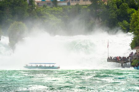 Neuhausen am Rheinfall, Switzerland - 23 July 2019. Waterfall on the river Rhine in the city of Neuhausen am Rheinfall in Switzerland. Tourists standing at the rushing waterfall flows.のeditorial素材