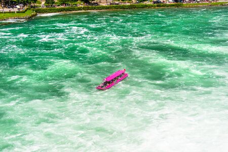 Neuhausen am Rheinfall, Switzerland - 23 July 2019. Waterfall on the river Rhine in Neuhausen am Rheinfall, Schaffhausen in Switzerland. Boats carrying tourists on the river near the waterfall.のeditorial素材