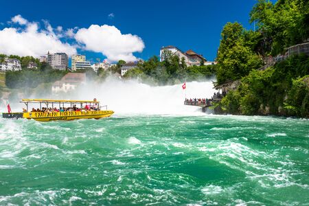 Neuhausen am Rheinfall, Switzerland - 23 July 2019. Waterfall on the river Rhine in Neuhausen am Rheinfall, Schaffhausen in Switzerland. Boats carrying tourists on the river near the waterfall.のeditorial素材