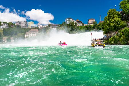 Neuhausen am Rheinfall, Switzerland - 23 July 2019. Waterfall on the river Rhine in Neuhausen am Rheinfall, Schaffhausen in Switzerland. Boats carrying tourists on the river near the waterfall.のeditorial素材