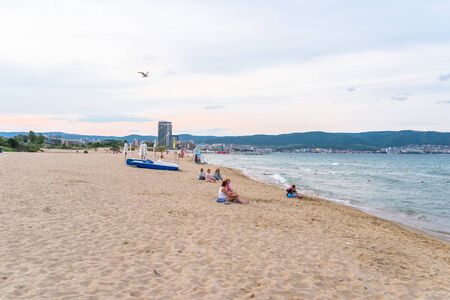 Sunny Beach, Bulgaria July 13, 2019. Several tourists sitting on the beach before sunset on a cloudy day.のeditorial素材
