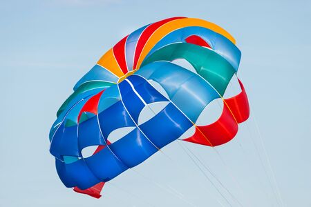 Close up shot of a colorful parachute used for parasailing pulled by a motorboat.