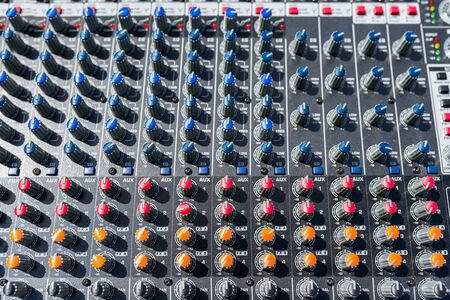 Close up photo of a professional sound mixer with many adjustments, knob switches and buttons of audio mixer control panel.の写真素材
