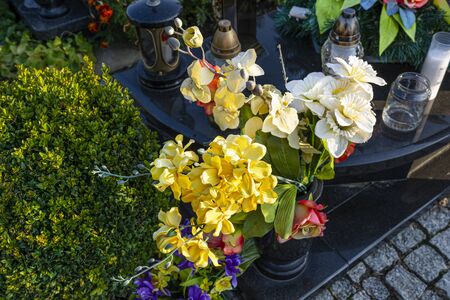 Artificial flowers and candles lie on the tombstone in the cemetery.