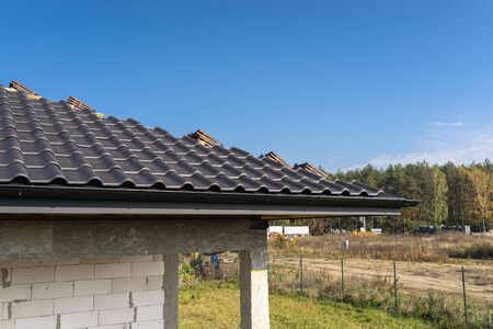 The roof of a single-family house covered with a new ceramic tile in anthracite, against the blue sky.の写真素材