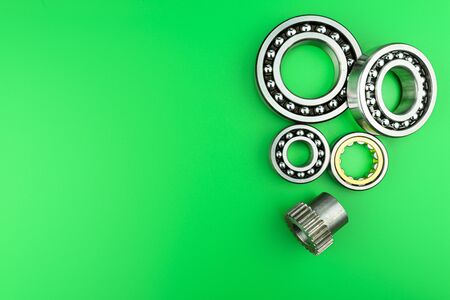 Ball bearing lying on a green background with copy space on the left side. Flat view from above.の写真素材