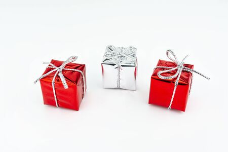 Macro picture of two red and one silver, shiny wrapped gift with bow, isolated on a white background.の写真素材