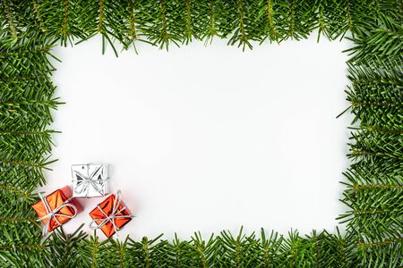 Frame made of fir branches, in the lower left corner three wrapped gifts, isolated on a white background.の写真素材