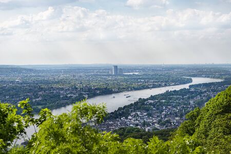 River Rhein in western Germany flowing along the city against the sky with clouds. Visible barges...