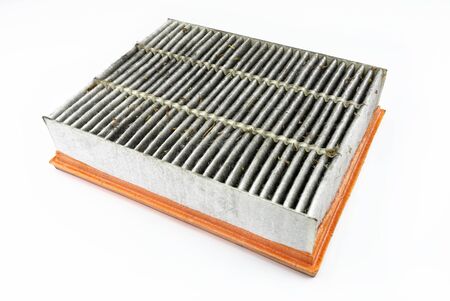 Worn and dirty rectangular car air filter, visible leaves and dirt, isolated on white background...