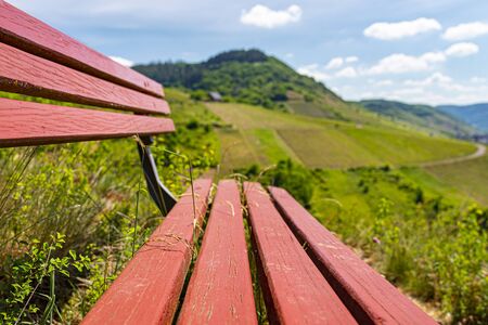 A red bench standing on the hill of the winery, in the background beautiful wineries in the spring.