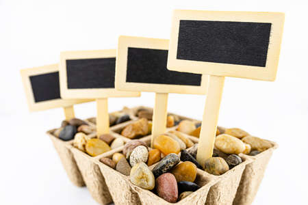 Four, wooden blank boards, label with stick, stuck in a cardboard extruder filled with decorative...