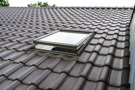 One open roof window in the attic, visible anthracite ceramic tiles.の写真素材