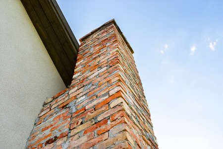 A red ceramic brick chimney standing at the rear of the building, by the facade, with a blue sky in the background.の写真素材