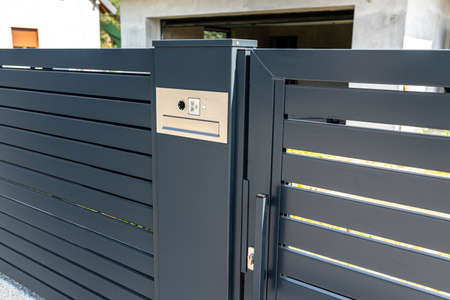 A modern videophone with a letterbox and a wireless card reader, mounted in panel fence in anthracite color, visible wicket.の写真素材