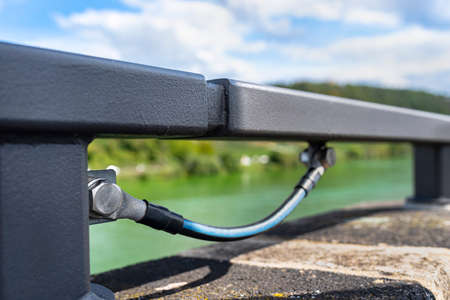 A grounding cable connecting the metal railings on the railway bridge.