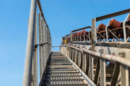 Close-up shot of the conveyor belt in the concrete plant with transport rollers, visible metal stairs and railings.の写真素材