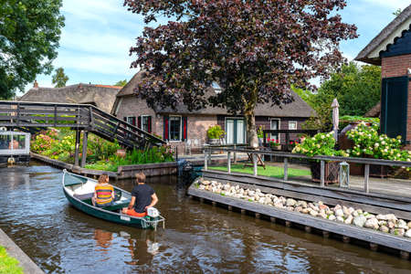 Giethoorn, Netherlands - 13 September 2020. Tourists sailing on rented boats on the canal between houses in the famous village of Giethoorn. The village is called the Venice of the Netherlands.のeditorial素材