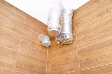 Modern gas boiler room with brown ceramic tiles imitating wood, visible air inlet and outlet, prepared for mounting the device used for home energy recovery ventilation.の写真素材