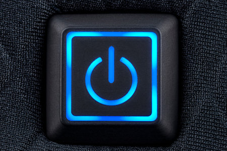 Macro shot of a plastic button with a blue power symbol, sewn into modern clothing, top view.