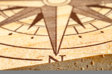 Macro shot of a compass painted on a wooden plank, small depth of field, close-up to the north...