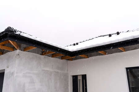 Single-family house roof covered with snow against a cloudy sky. Visible system chimney, doors,...